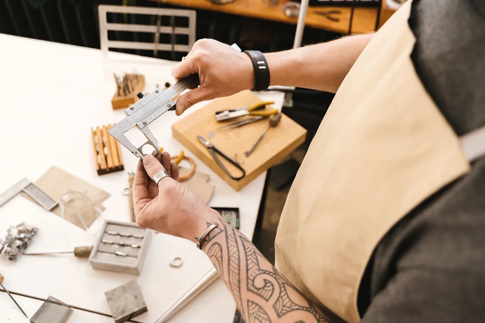 Craftsperson measuring a small metal component with a vernier caliper
