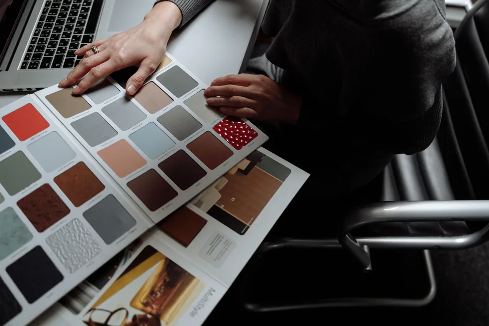 Hands comparing color and material swatches at a desk